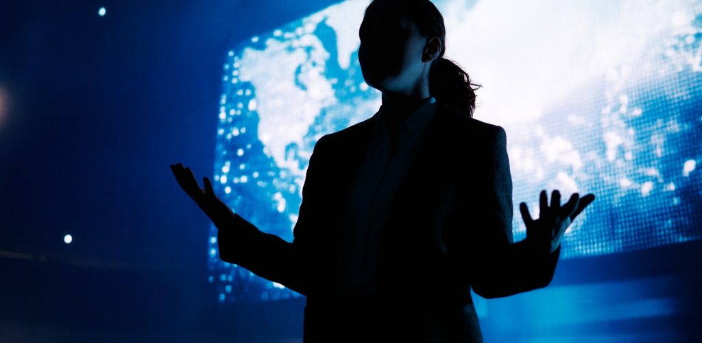 A woman is speaking on stage about the future of AI technologies.